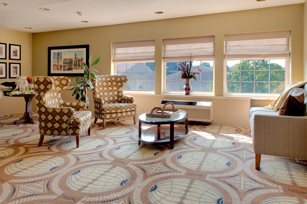A cozy living room with patterned chairs, abundant natural light, and a central coffee table.