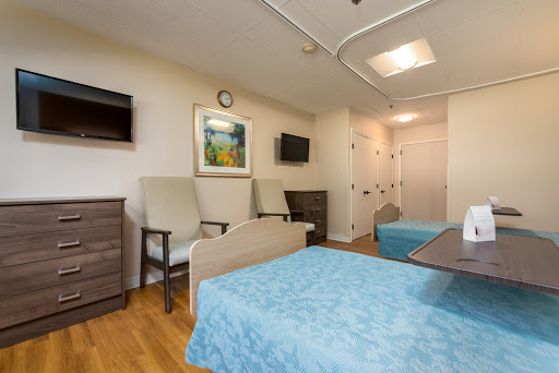 A well-furnished hospital room featuring two beds, seating area, and modern amenities.