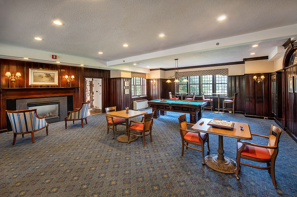 A cozy game room featuring a pool table, several seating areas, and a fireplace.
