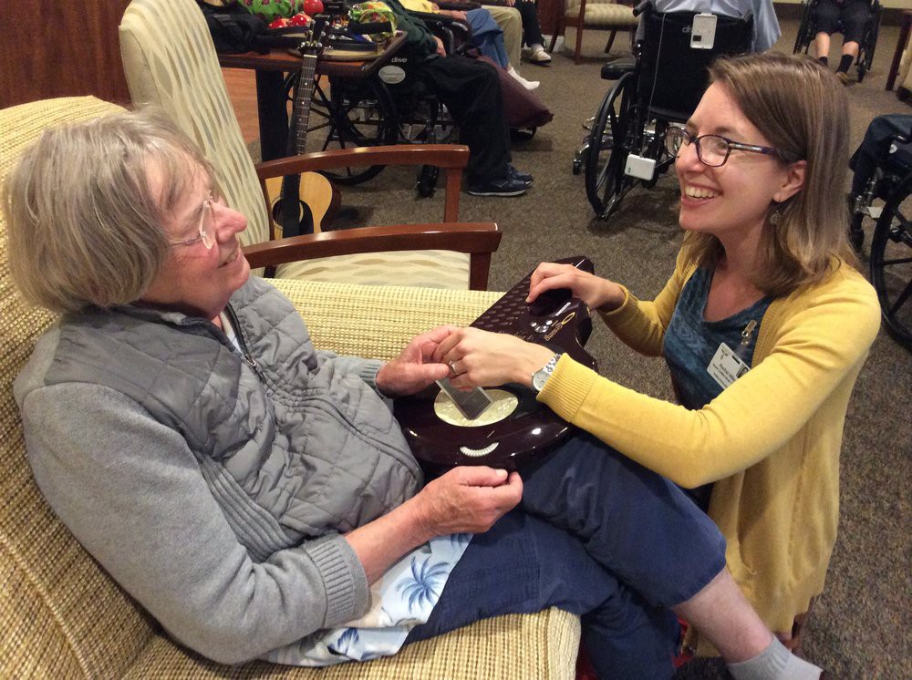 A caregiver smiling while interacting with an elderly person.
