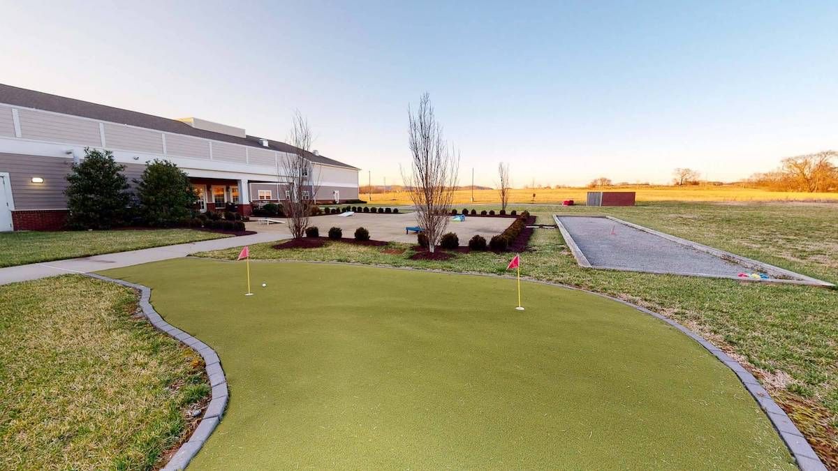 A putting green next to a modern building during sunset.