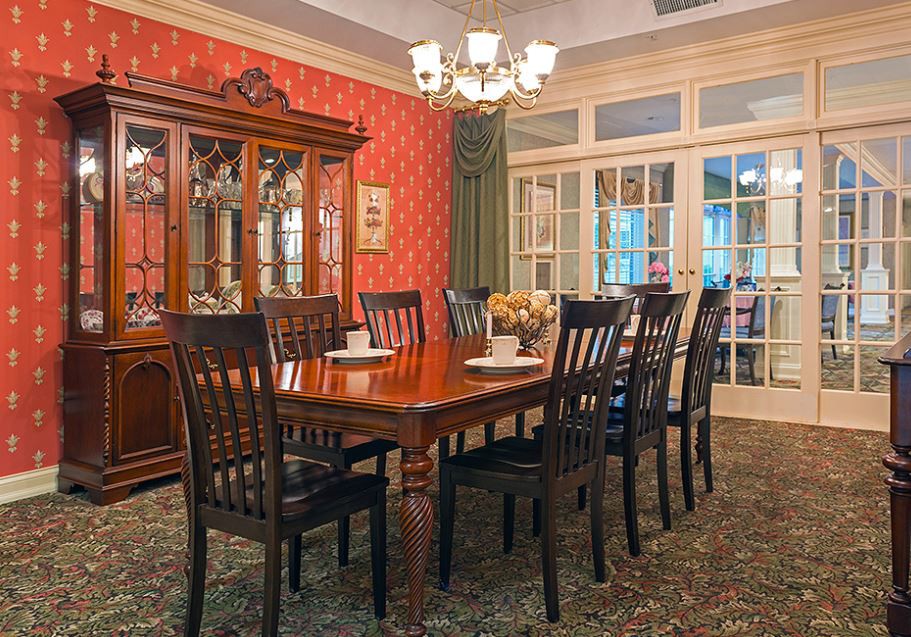 A traditional dining room with a long wooden table, matching chairs, and a chandelier.