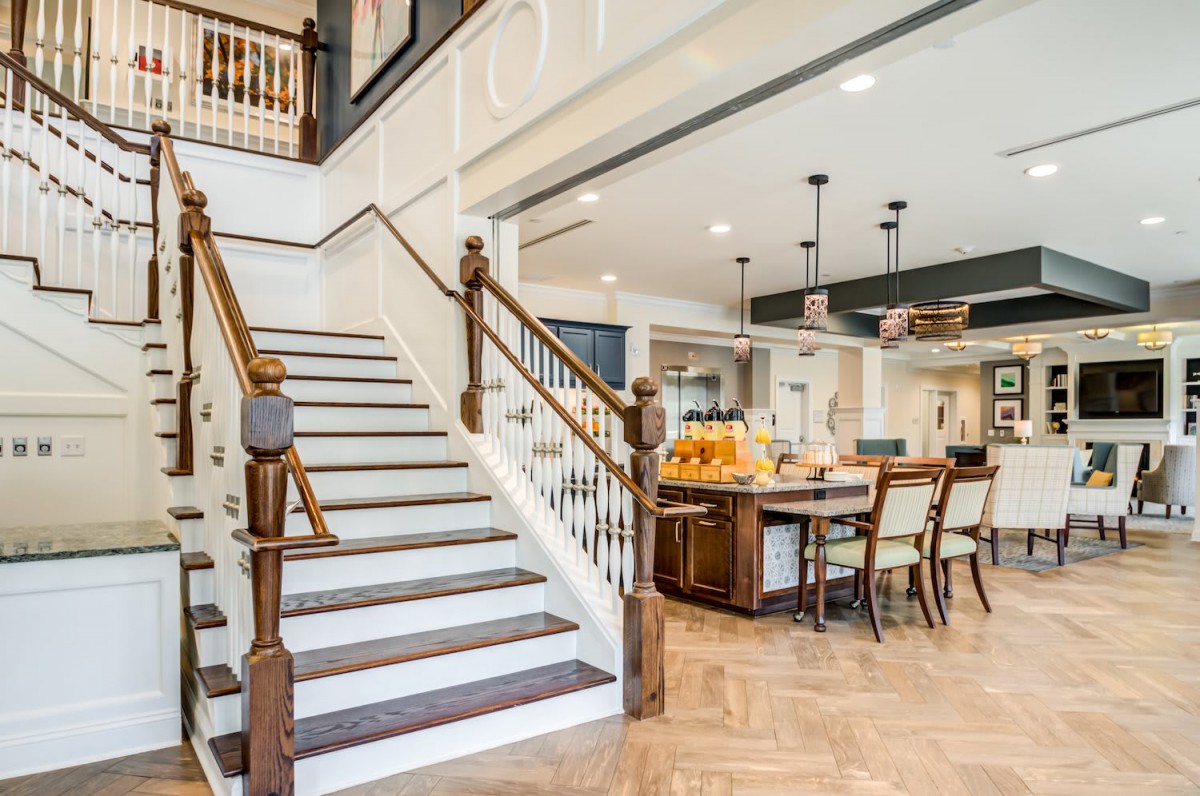 A modern open-concept kitchen and staircase with hardwood floors and elegant pendant lighting.