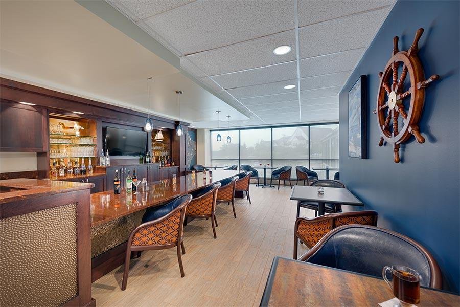 Modern bar interior with seating and large windows.