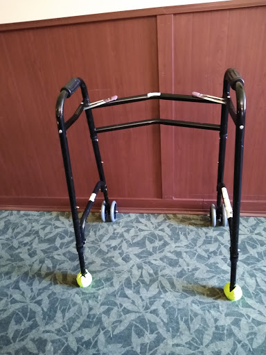 A black walker with wheels, designed to assist individuals with mobility.