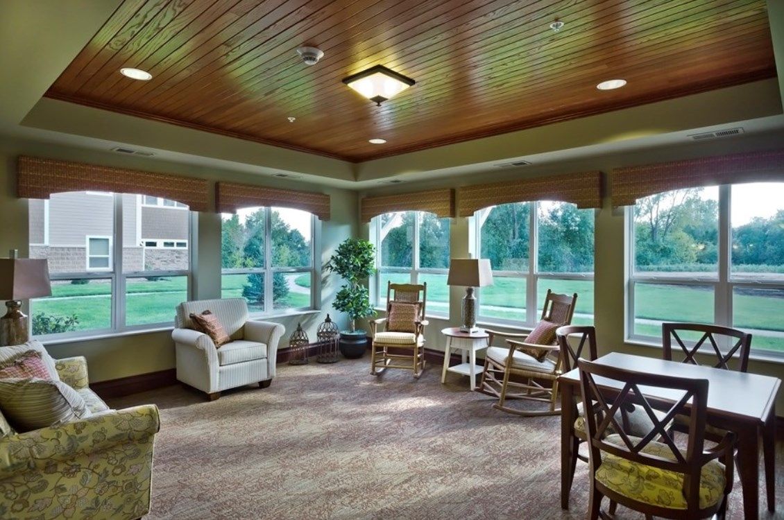 A cozy living room with comfortable seating and large windows offering a view of greenery outside.