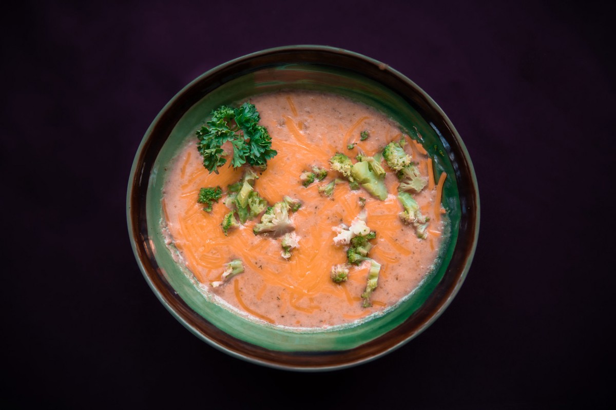 A bowl of creamy soup garnished with cilantro and broccoli.