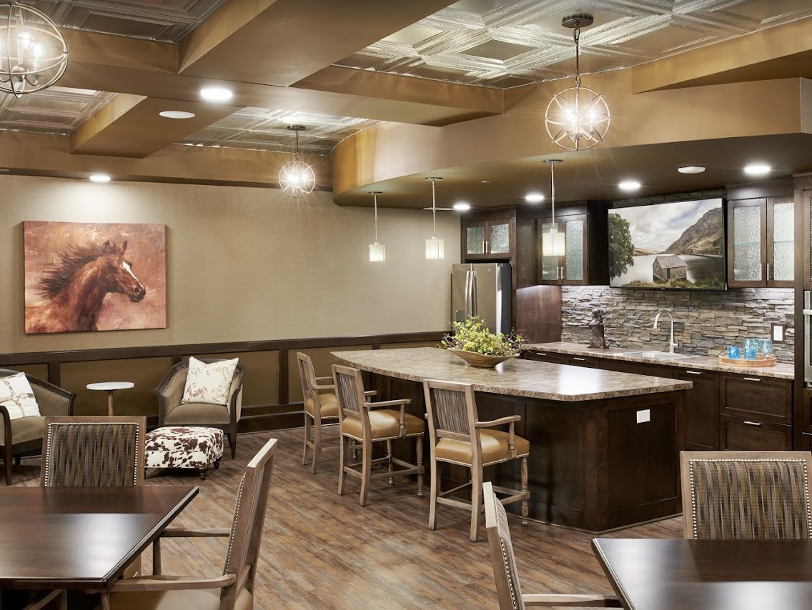 A modern restaurant interior featuring a bar counter with wooden chairs, stylish lighting fixtures, and contemporary decor.