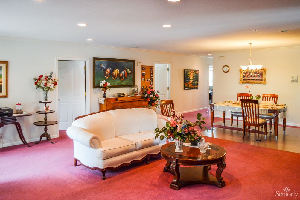 A cozy living room with vintage furnishings, highlighted by a white sofa and a wooden coffee table on a pink carpet.