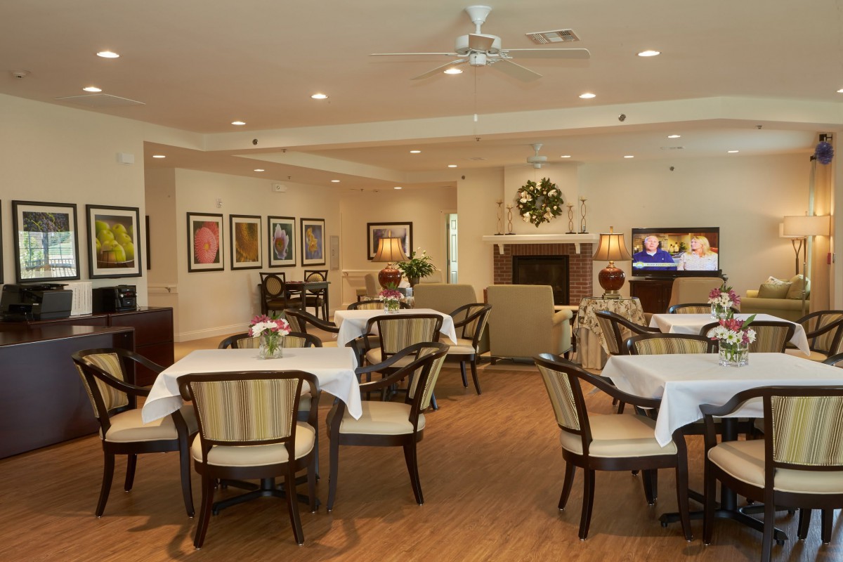 A cozy dining area with tables and chairs, featuring a fireplace and elegant decor.