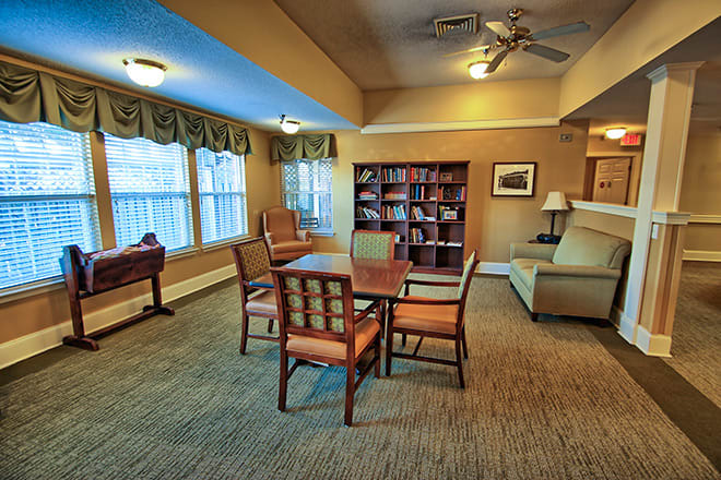 A cozy living room with a table, chairs, and a bookshelf.