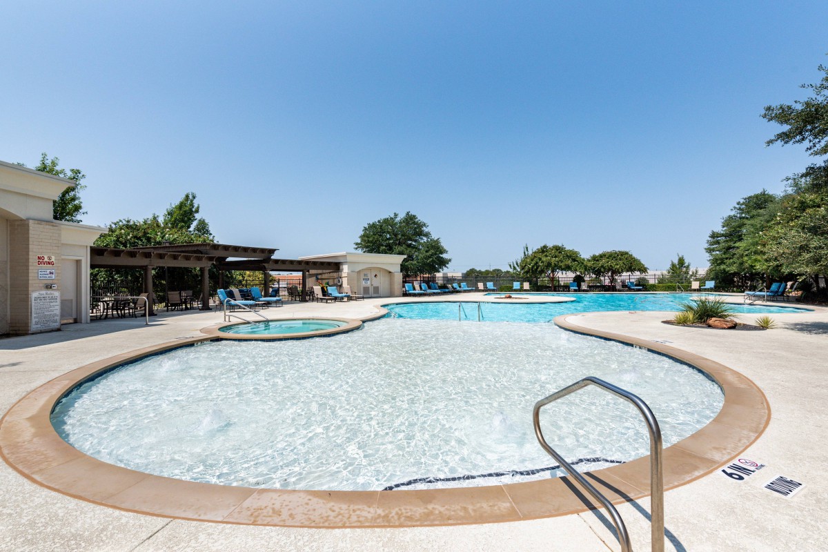 An inviting outdoor swimming pool under a clear blue sky, perfect for summer relaxation.