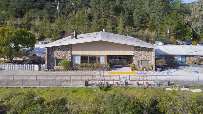 A stone-clad building nestled against a forested hillside.