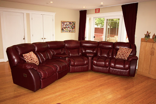 A cozy living room featuring a burgundy leather sectional sofa with decorative pillows.