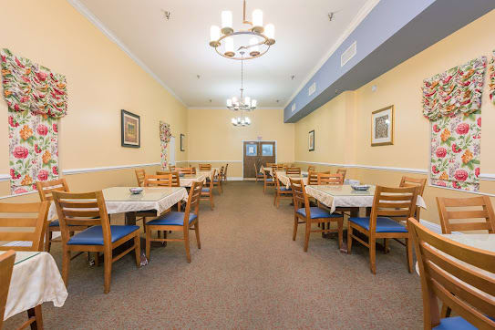 A well-lit dining room with multiple tables and chairs, decorated with wall art.