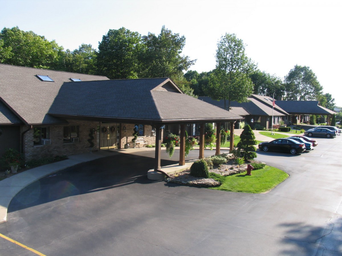 A sunny day view of a building with a carport and surrounding trees.