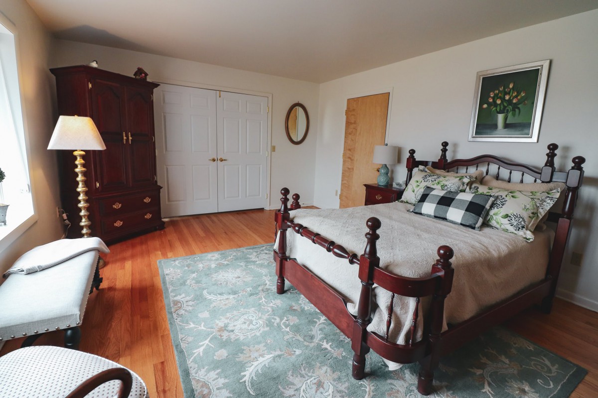 A cozy bedroom with wooden furniture and a patterned area rug.