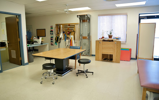 A well-equipped physical therapy room with a central therapy table and various rehabilitation tools.