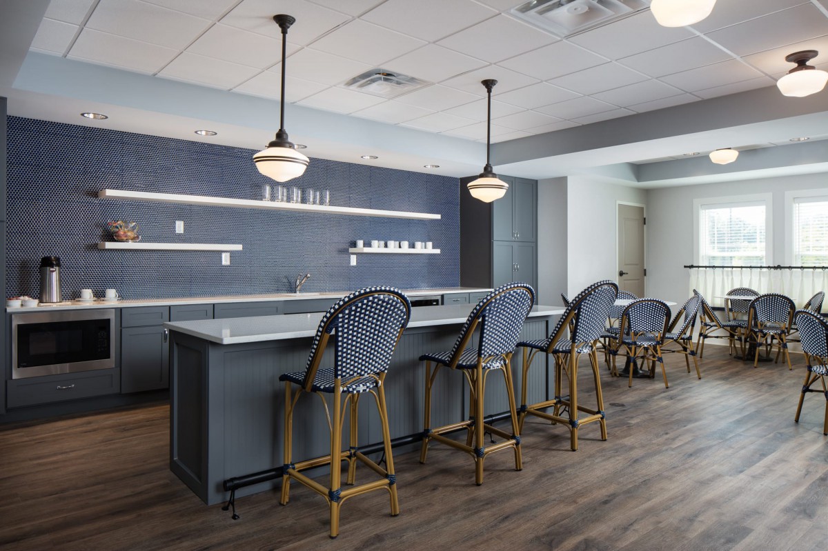 A modern kitchen interior with bar stools and pendant lighting.