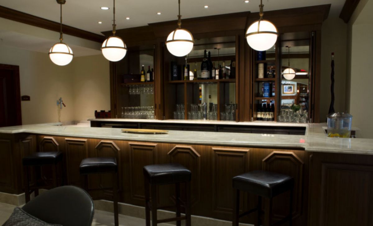 A stylish bar interior featuring a polished counter, modern lighting, and comfortable seating.