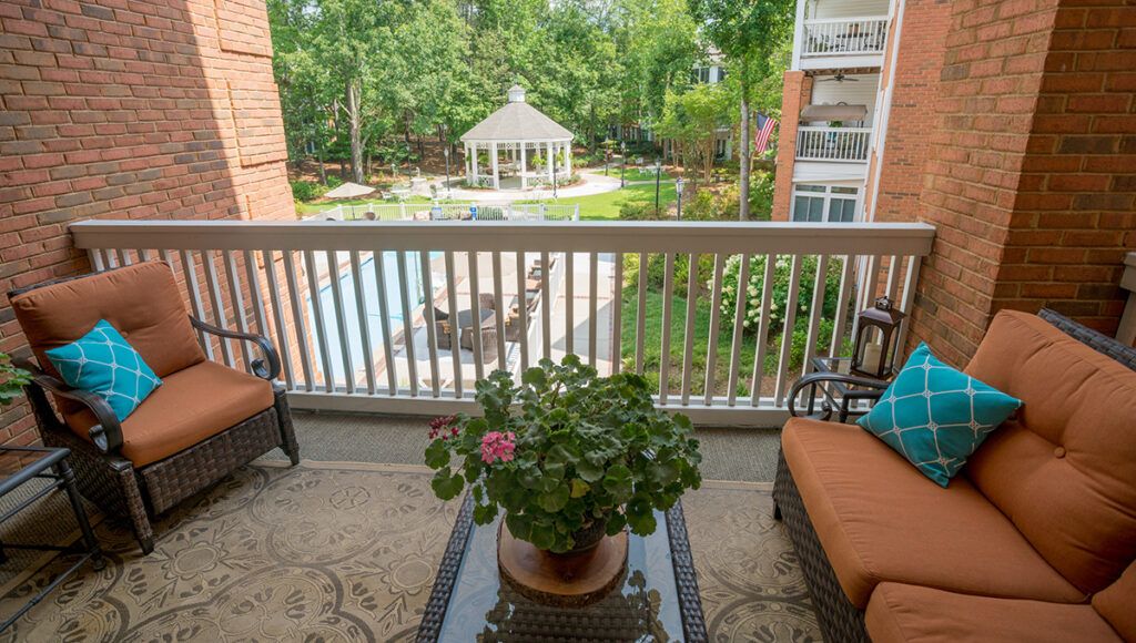 A peaceful balcony view overlooking a garden area with a gazebo and pool at an apartment complex.