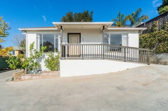 A single-story house with a front ramp and driveway under a clear blue sky.