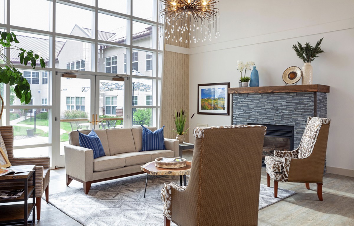 A modern living room with elegant furniture, large windows, and a decorative chandelier.