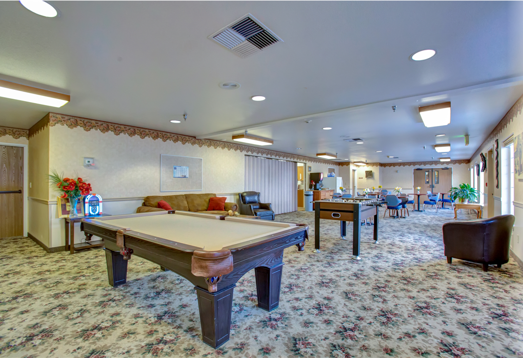 A spacious recreation room featuring a pool table, foosball table, and comfortable seating areas.