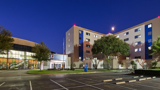 A modern hotel exterior illuminated at night, showcasing its architectural design and surroundings.