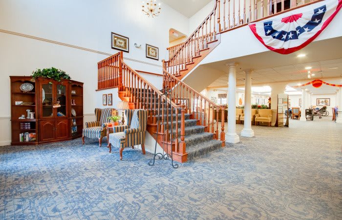 A spacious lobby featuring a grand wooden staircase and comfortable seating area.