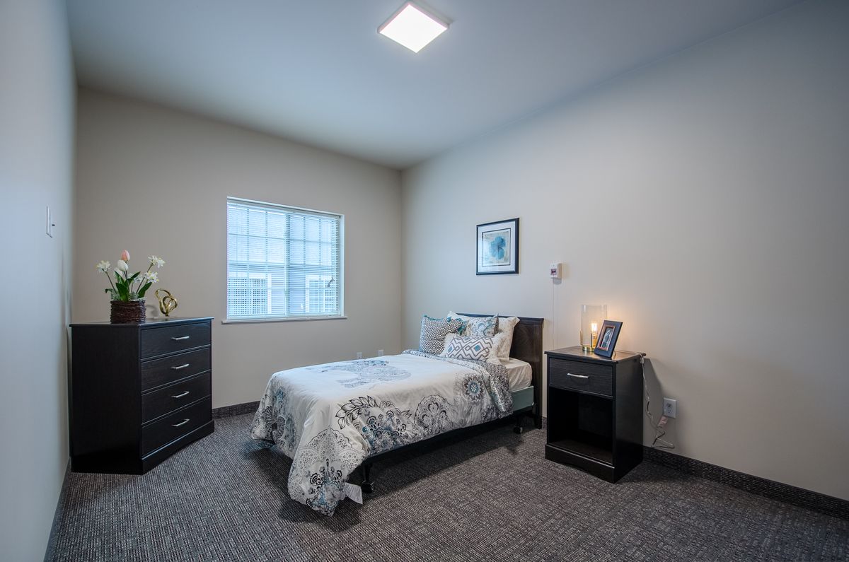 Minimalist bedroom with a single bed, nightstand, and dresser.