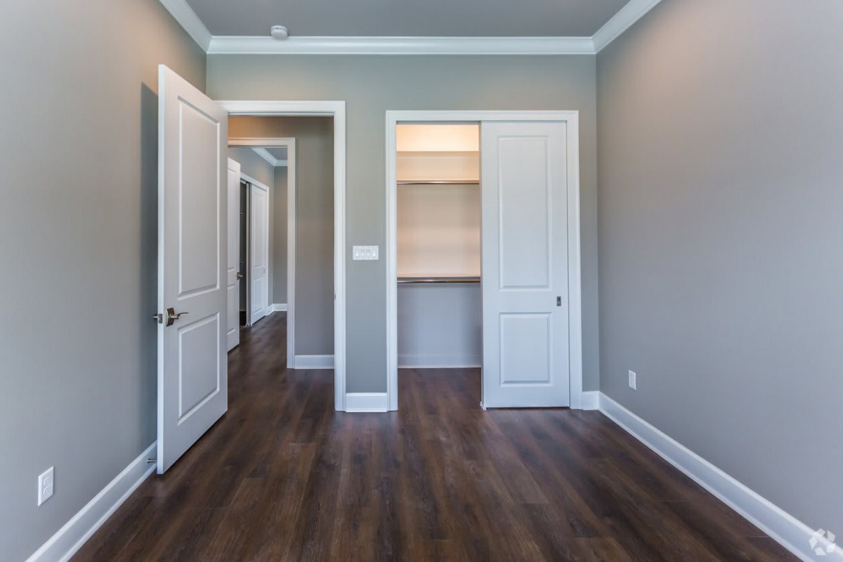 An empty room with wood flooring, featuring a closet and two doors.