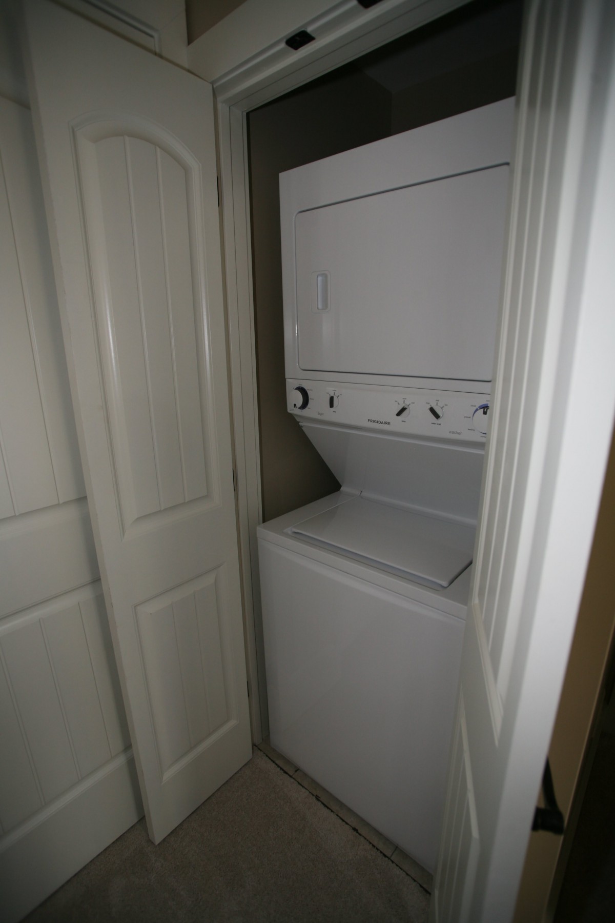 A compact stacked washer and dryer unit in a small closet.