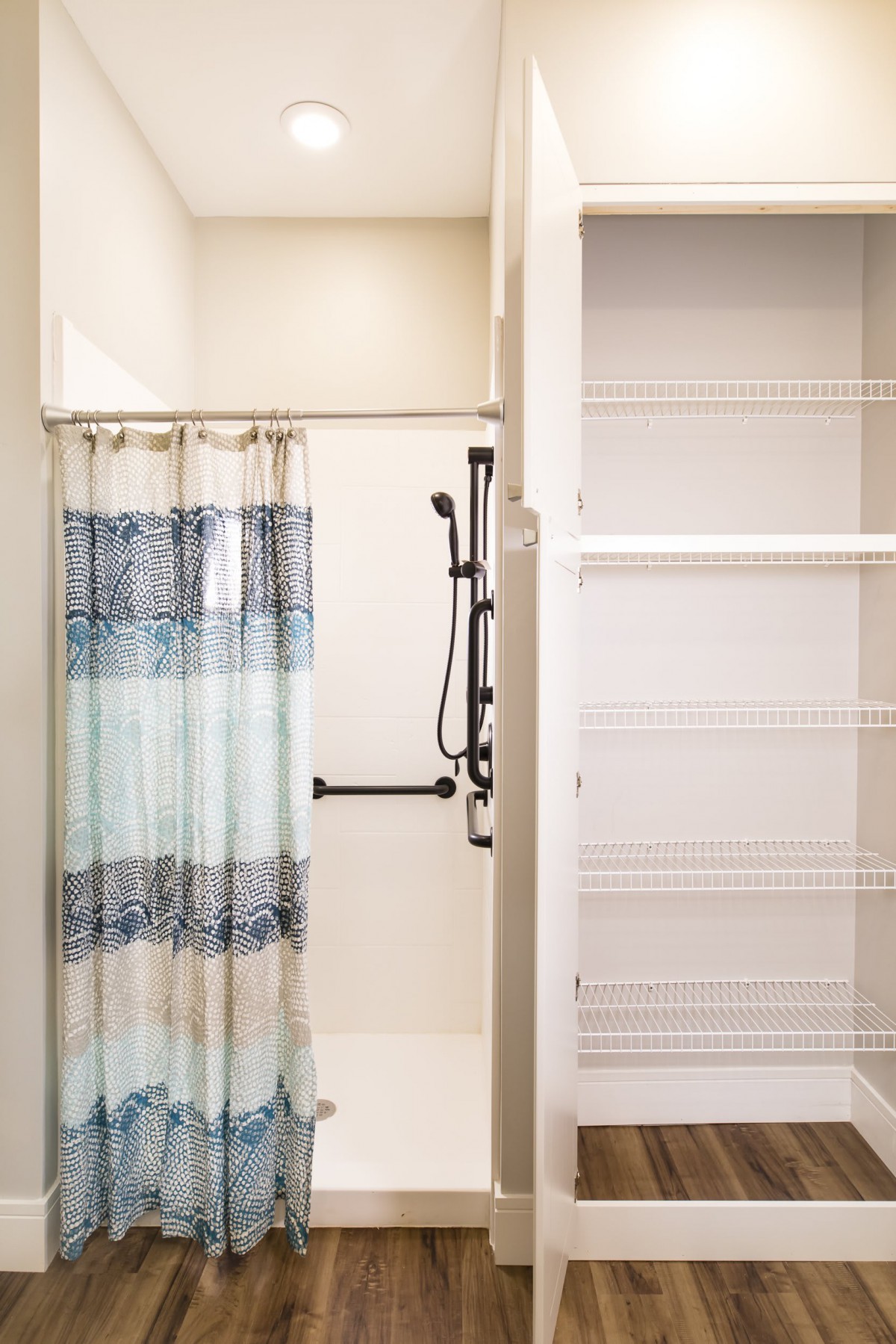 A bathroom featuring a shower with a striped curtain and built-in storage shelves.
