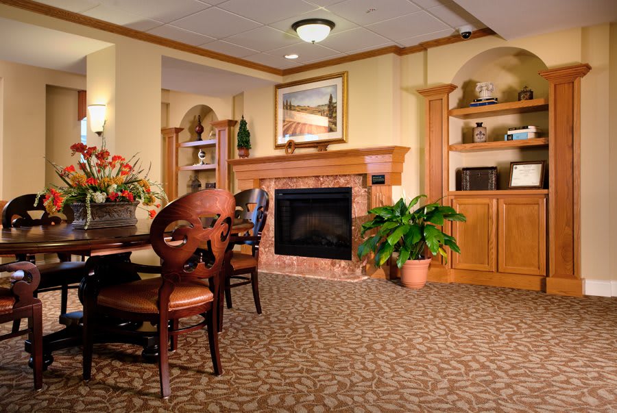 A cozy living room featuring a fireplace, dining table, and surrounding decor.