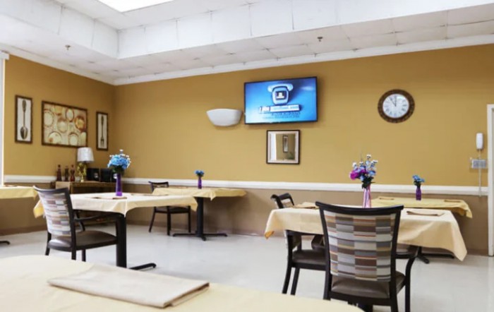 A dining area with tables, chairs, and a television on the wall.