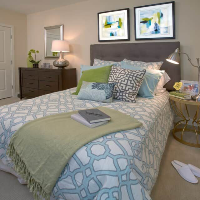 A modern bedroom featuring a stylish bed with patterned bedding, decorative pillows, and contemporary artwork on the wall.
