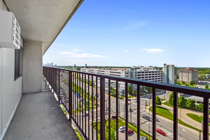 A view from a high-rise balcony overlooking an urban landscape with clear skies.
