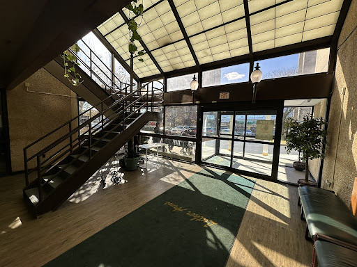 A bright and inviting lobby featuring a staircase, abundant natural light, and greenery.
