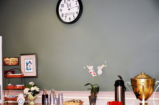 A cozy corner featuring a wall clock, decorative flowers, and refreshments.