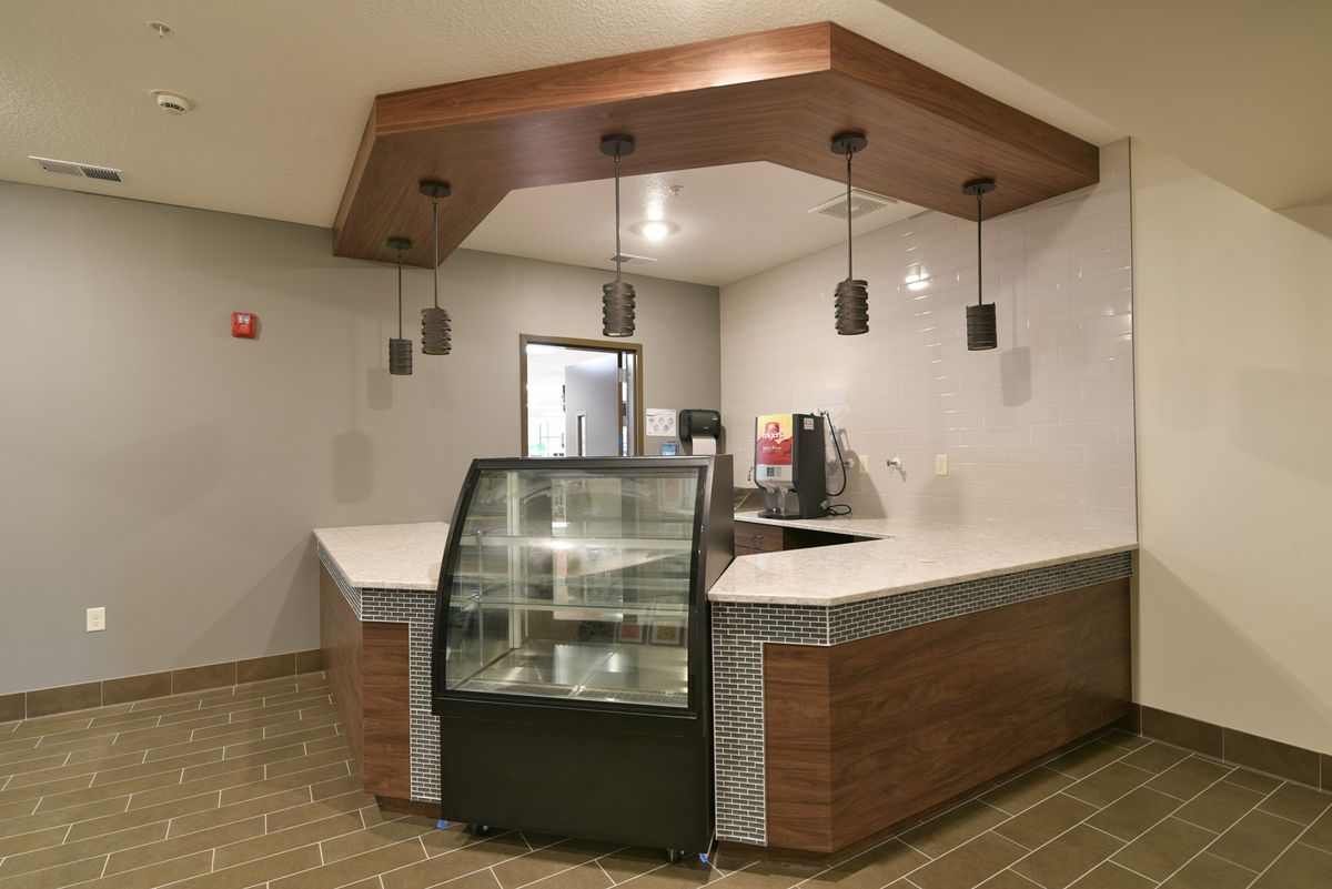 Modern cafe interior with an empty display case and pendant lighting.