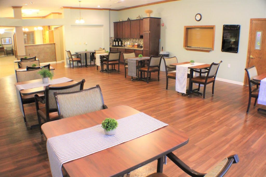 A cozy dining area with neatly arranged tables and chairs, featuring a wooden floor.