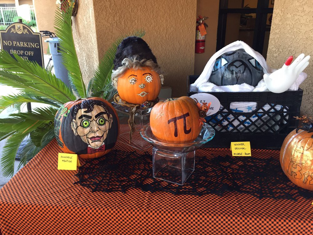 A display of creatively decorated pumpkins for Halloween, featuring painted designs and a pi symbol.