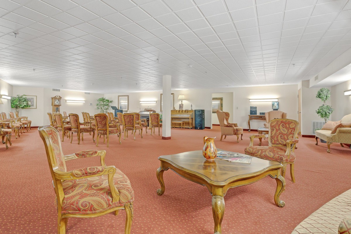 A spacious meeting room with elegant chairs and tables on a carpeted floor.