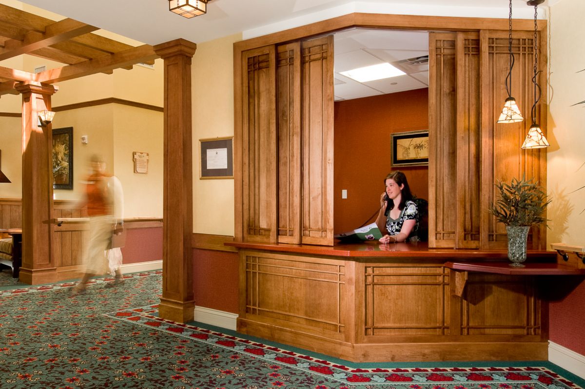 A reception area with a wooden desk and an employee speaking on the phone.