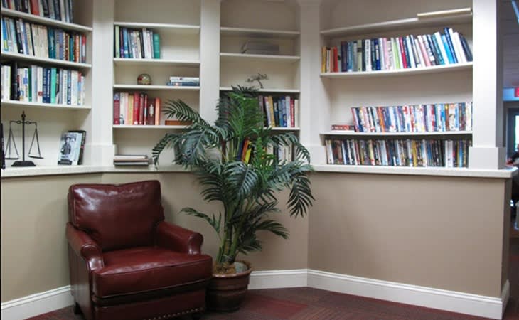 A cozy reading corner with a leather chair, bookshelves, and a potted plant.