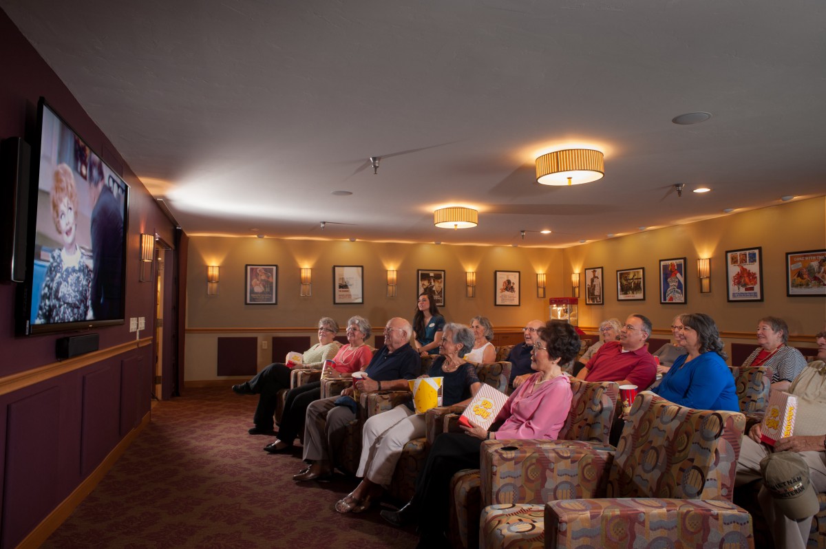 A group of people seated in a theater, watching a movie.