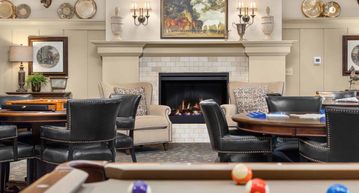A cozy living room with a fireplace, comfortable seating, and a pool table.