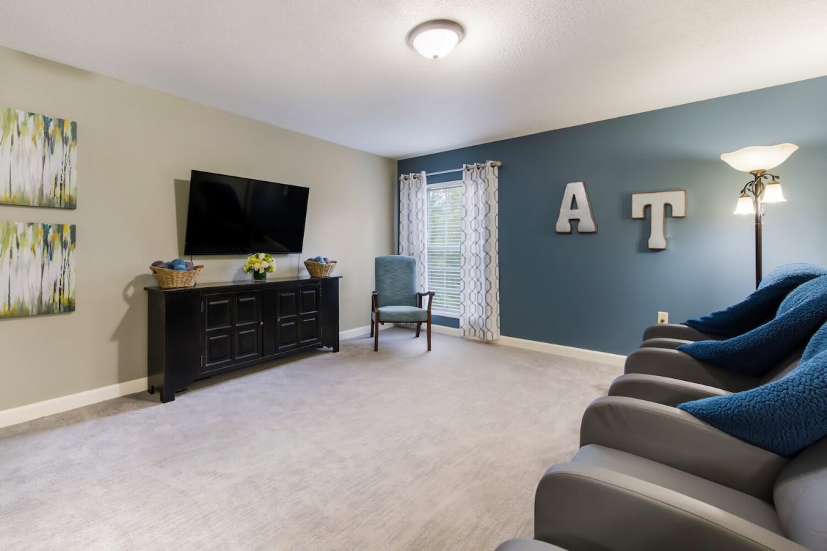 A cozy living room with a TV, comfortable seating, and decorative elements.