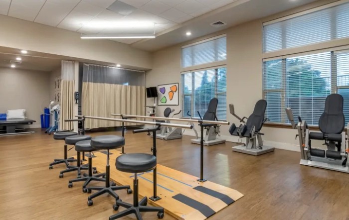 A spacious rehabilitation room equipped with exercise machines and therapy stations.